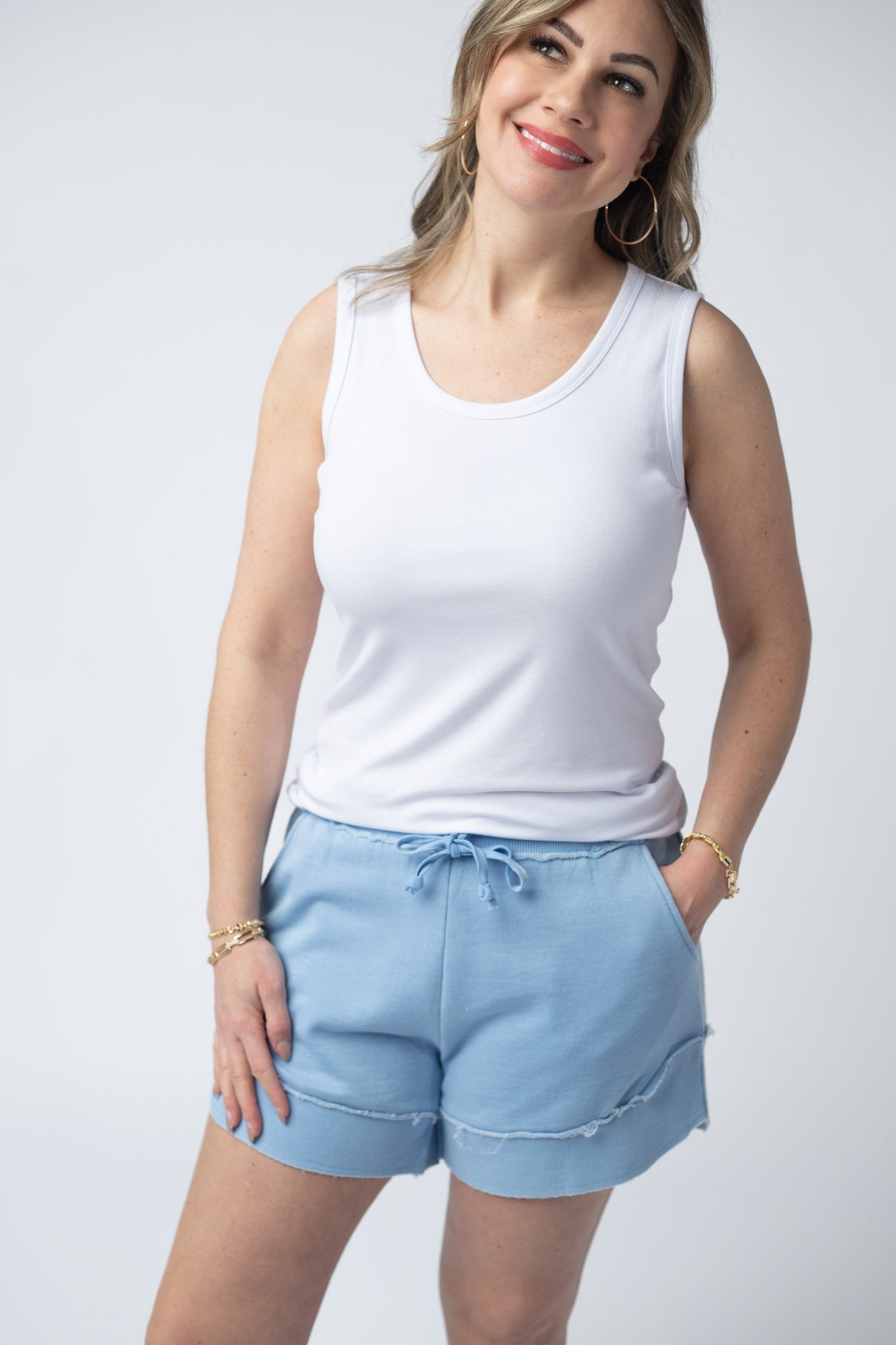 Women's French terry shorts in Dusty Blue with drawstring waist, side pockets, raw edge details, and side scoop hem