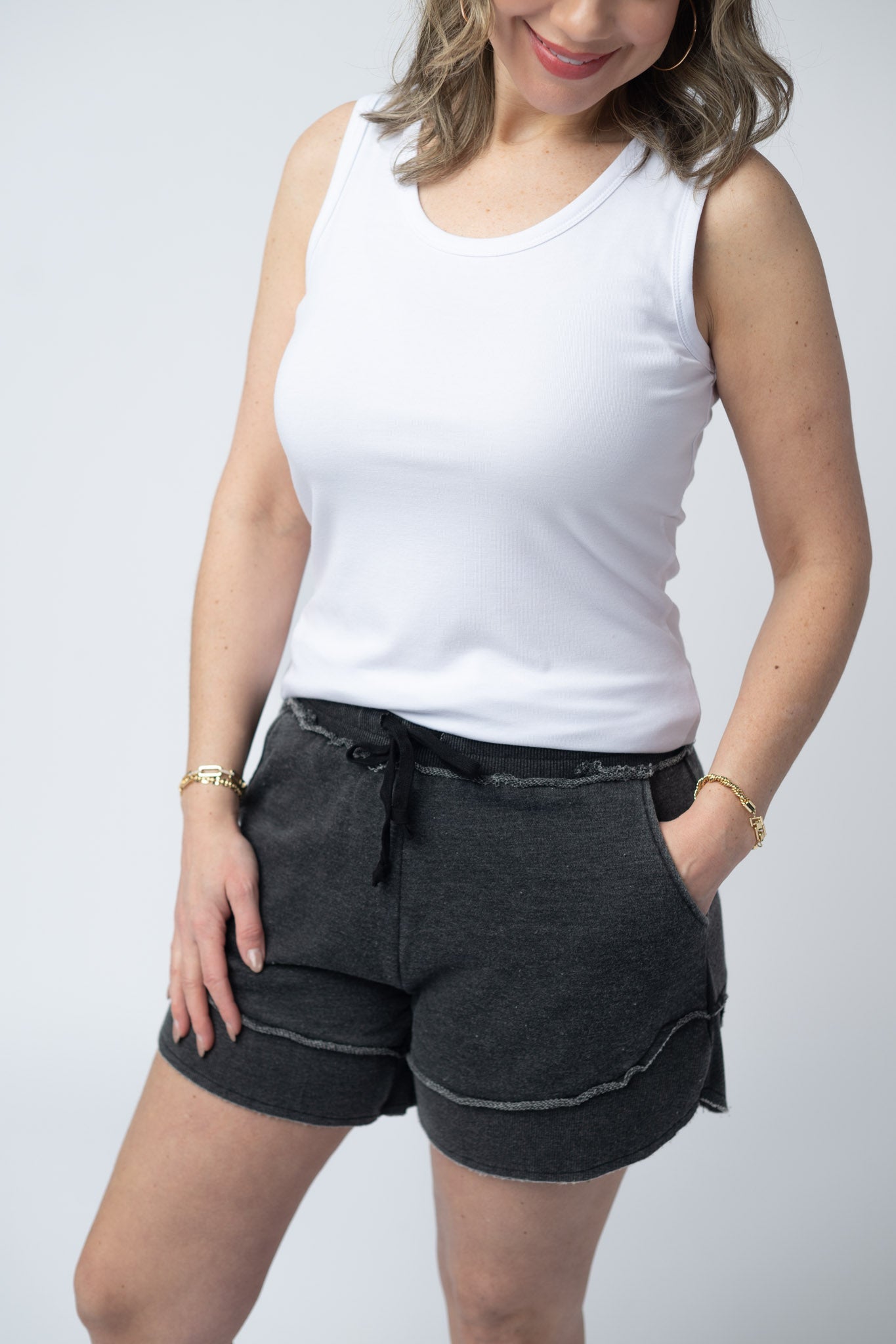 Women's French terry shorts in Black with drawstring waist, side pockets, raw edge details, and side scoop hem