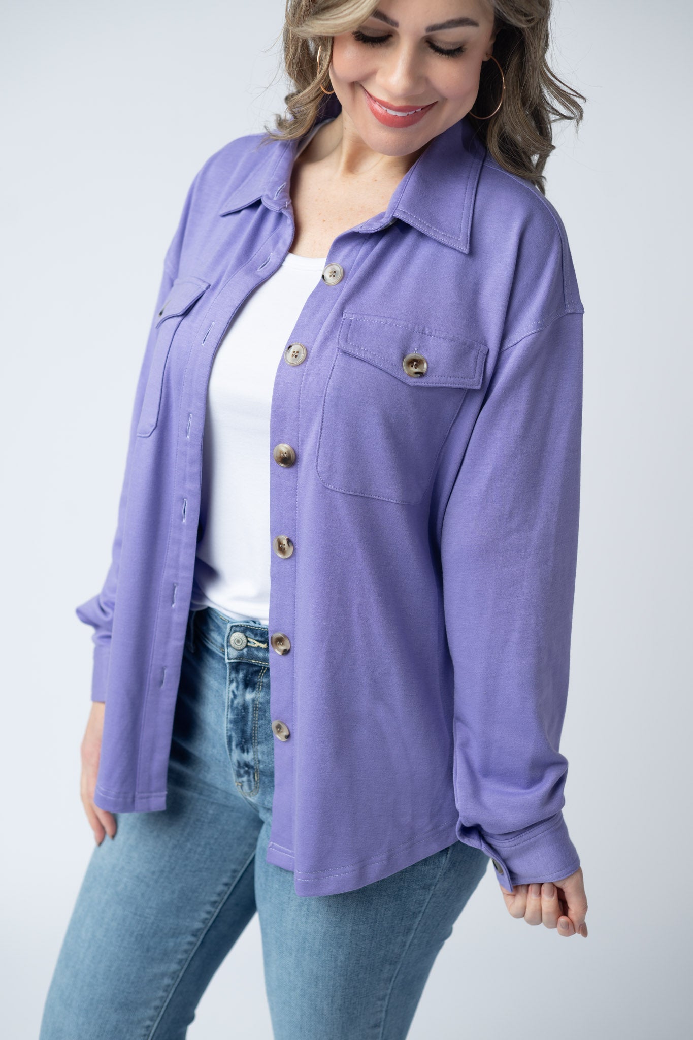 Woman wearing a lavender purple Brenna Button Down Top with breast pockets and button front, styled open over a white tank with jeans