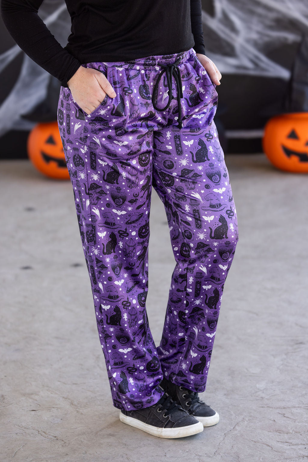 Purple witchy lounge pants with spell-themed icons, pockets, and drawstring