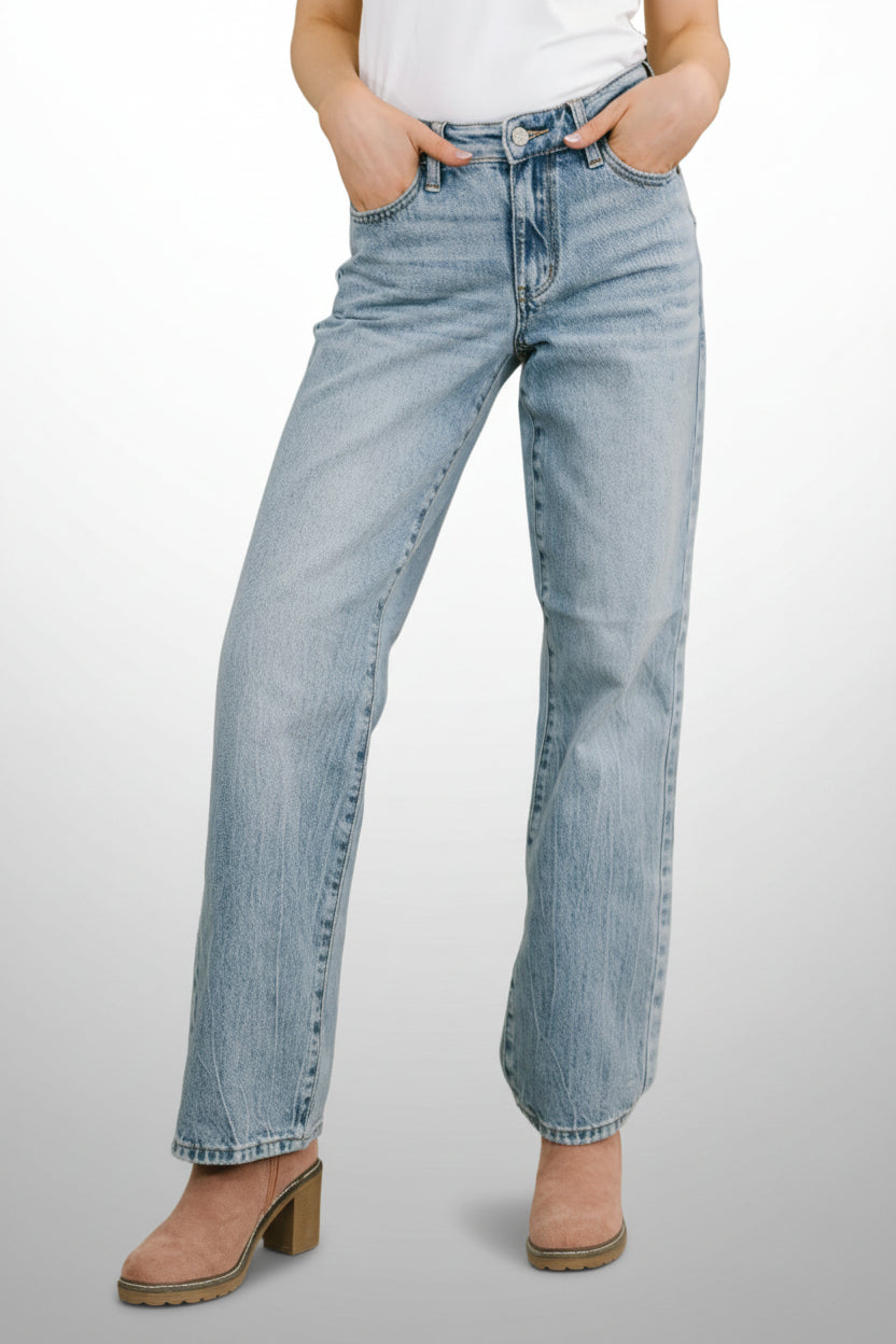 Woman wearing light wash mid rise straight leg jeans with distressed hem and white top