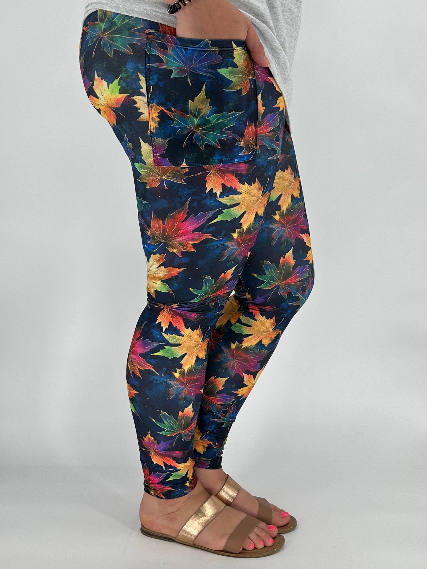 Colorful leaf-patterned leggings worn by a person on a plain background