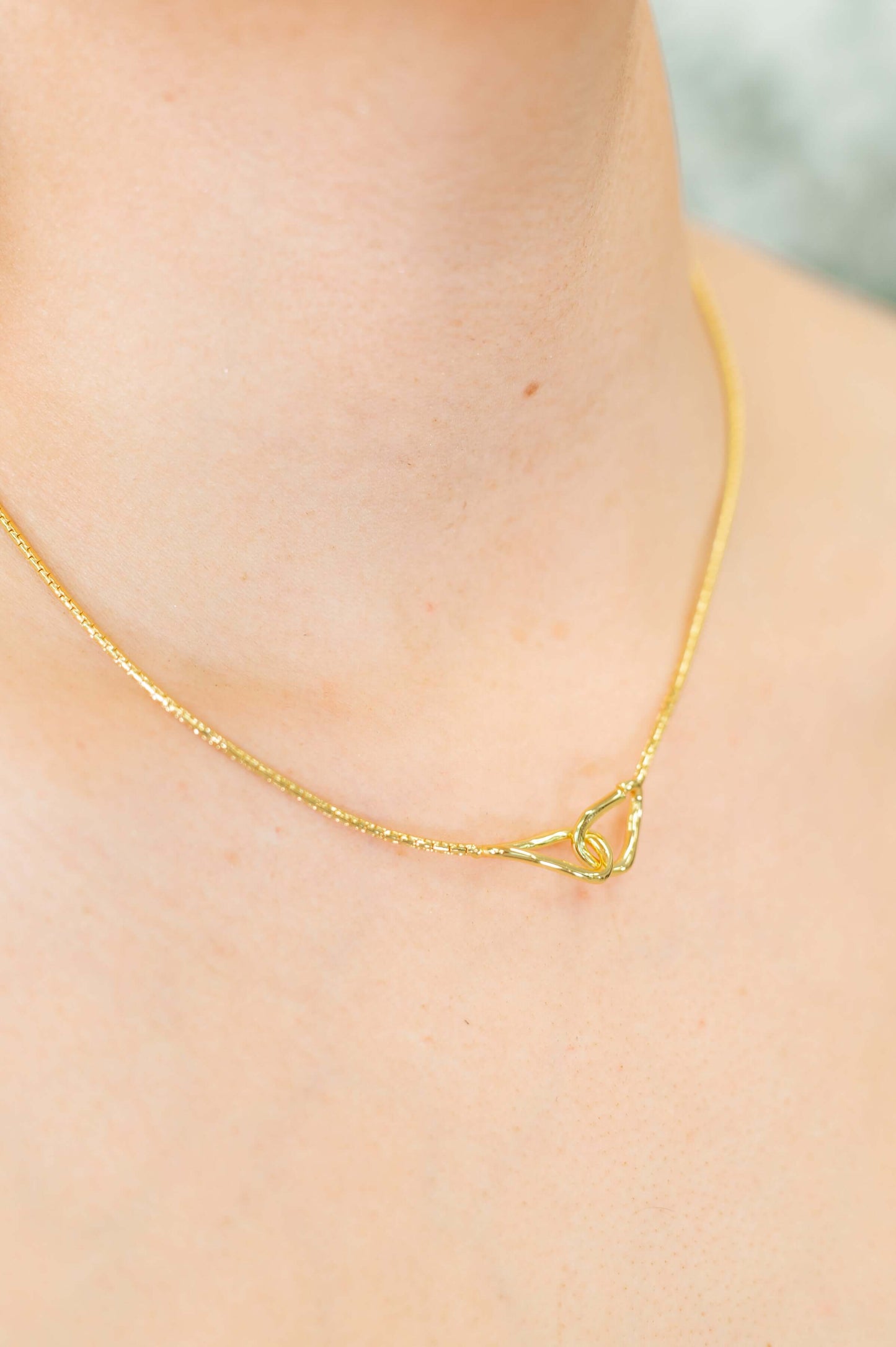 Close-up of gold plated hoop necklace with abstract pendant detail