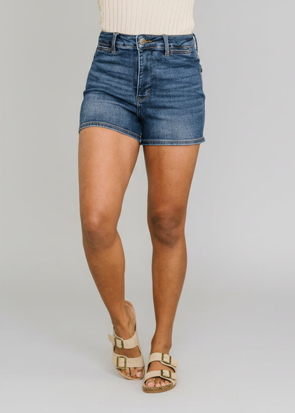 High waist tummy control shorts in medium wash denim with clean hem and classic five-pocket styling paired with a cream top and sandals