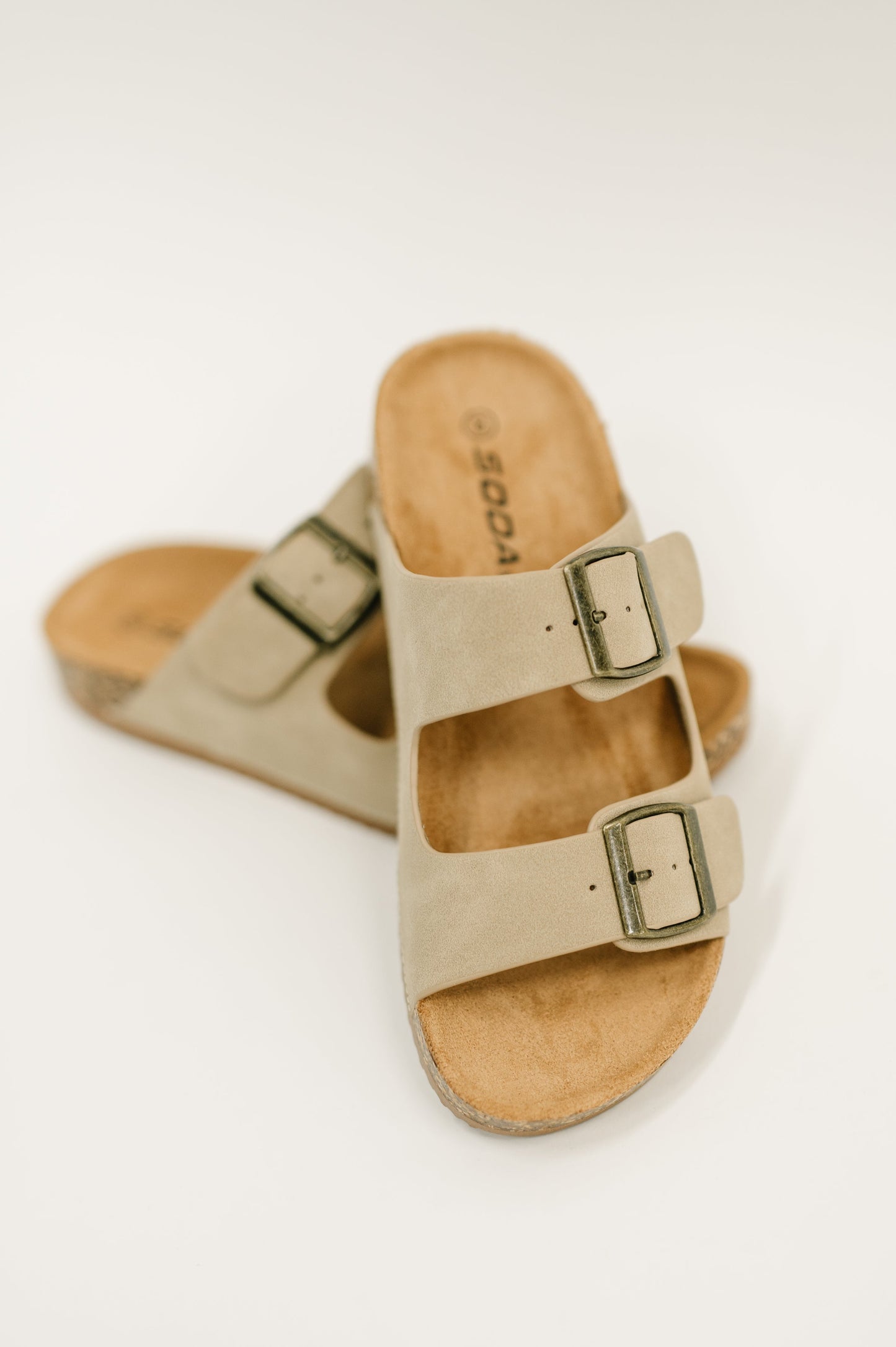 Women's double buckle slide sandals in light taupe faux nubuck with adjustable brass buckles and cork footbed