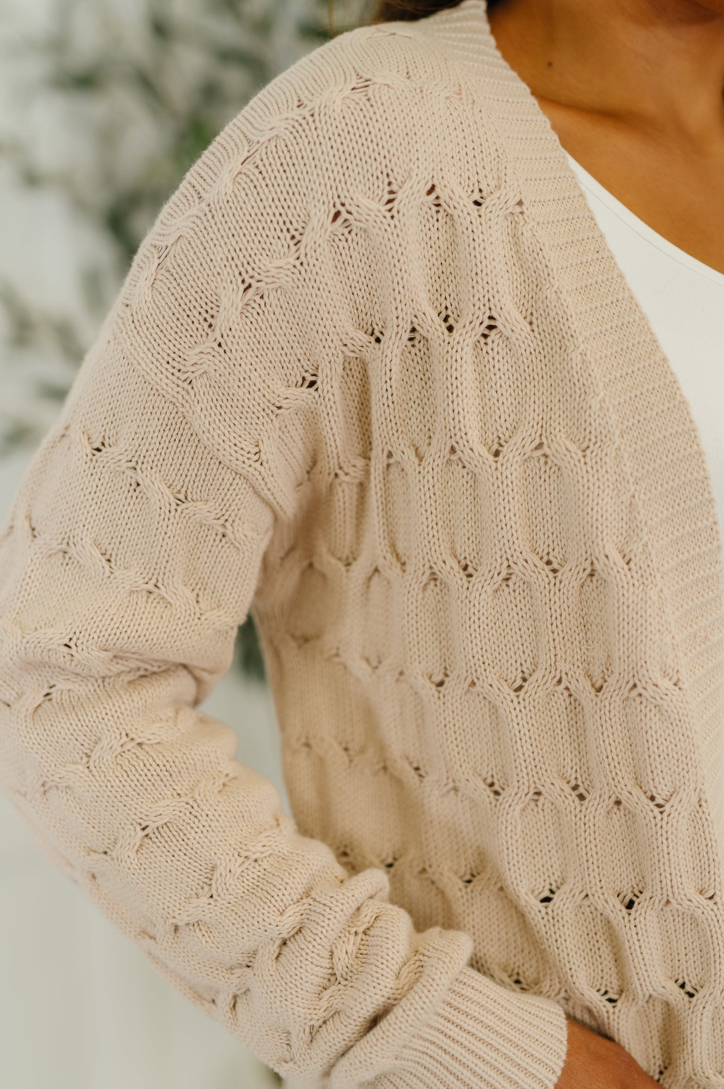 Woman wearing the Laugh Airily Cable Knit Cardigan in beige with open front and patch pockets.