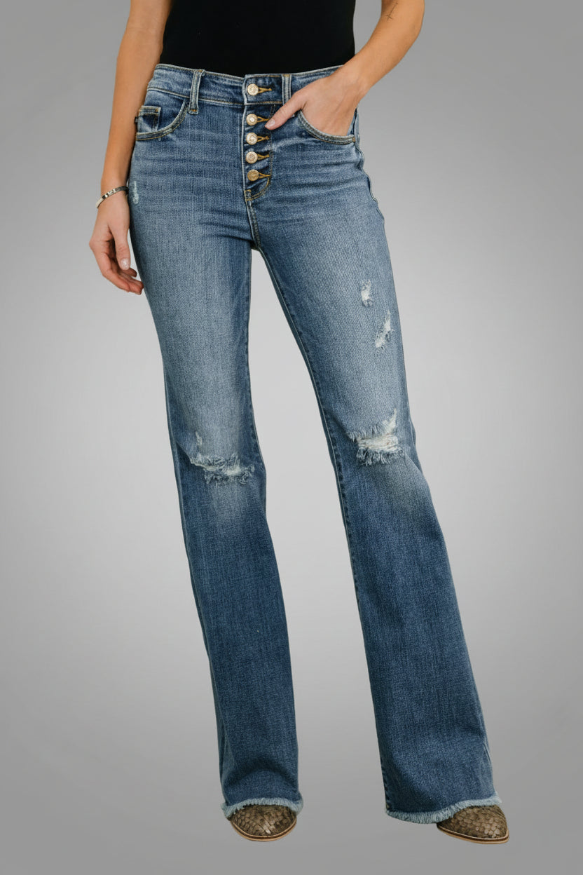 Woman wearing Marion medium wash mid rise flare jeans with button fly closure and destroy fray hem