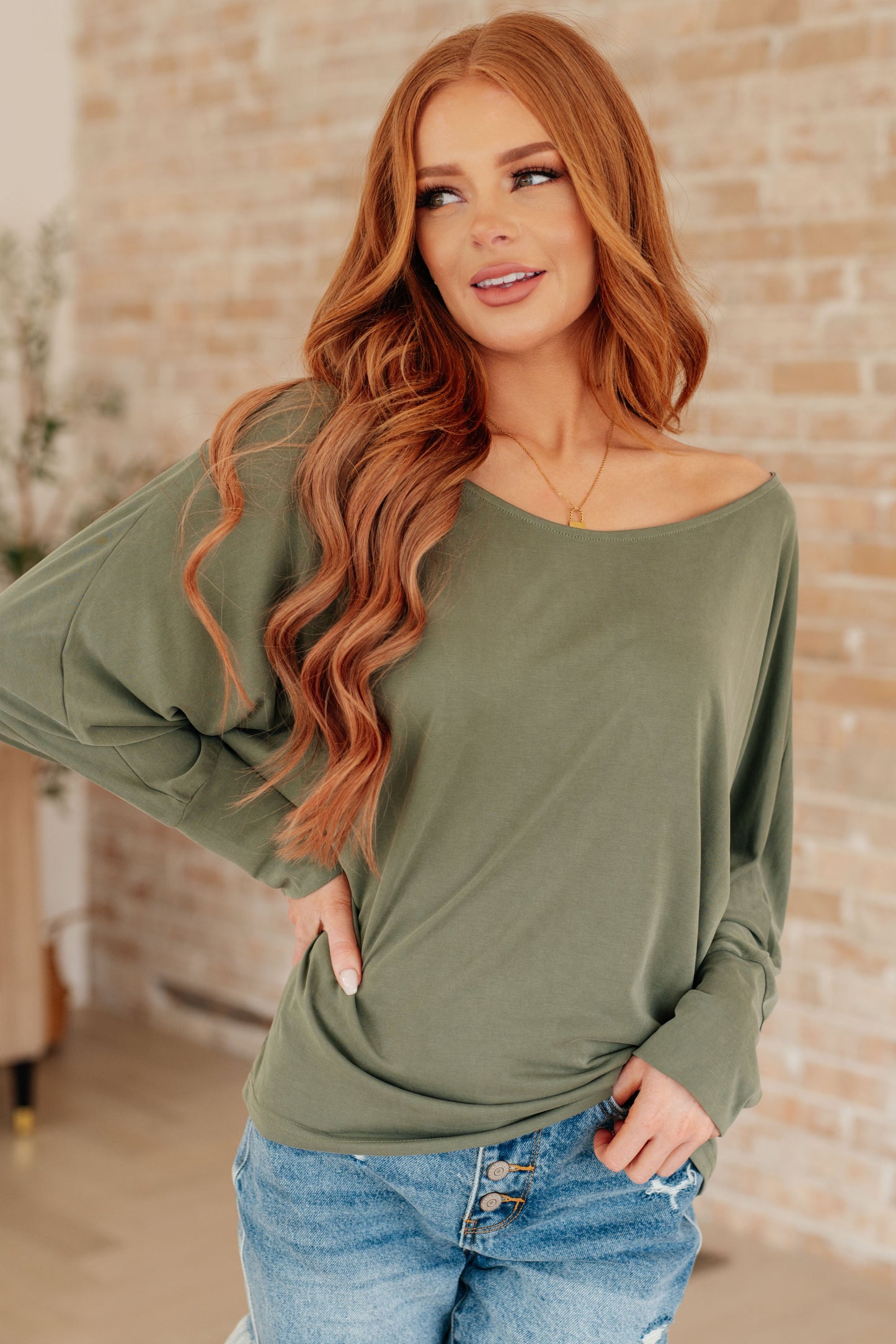 Model wearing olive green My Cozy Haven Long Sleeve Top with boat neckline and dolman sleeves
