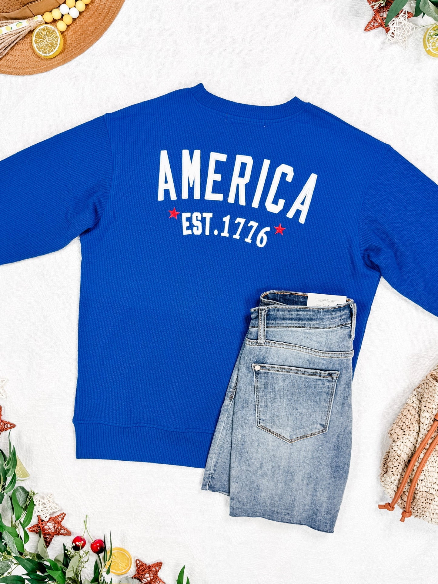 Blue sweatshirt with 'AMERICA EST. 1776' text on a white background