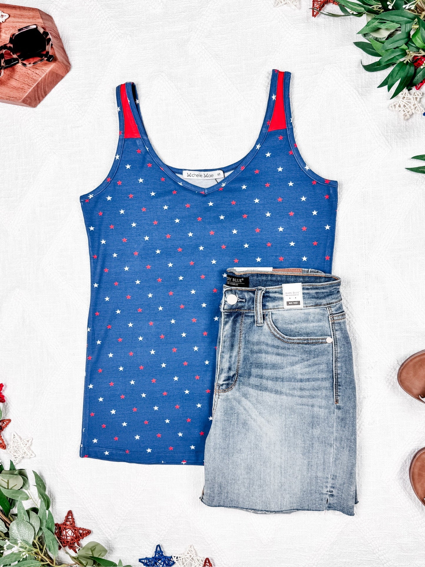 Blue tank top with red star pattern and denim skirt on a white background