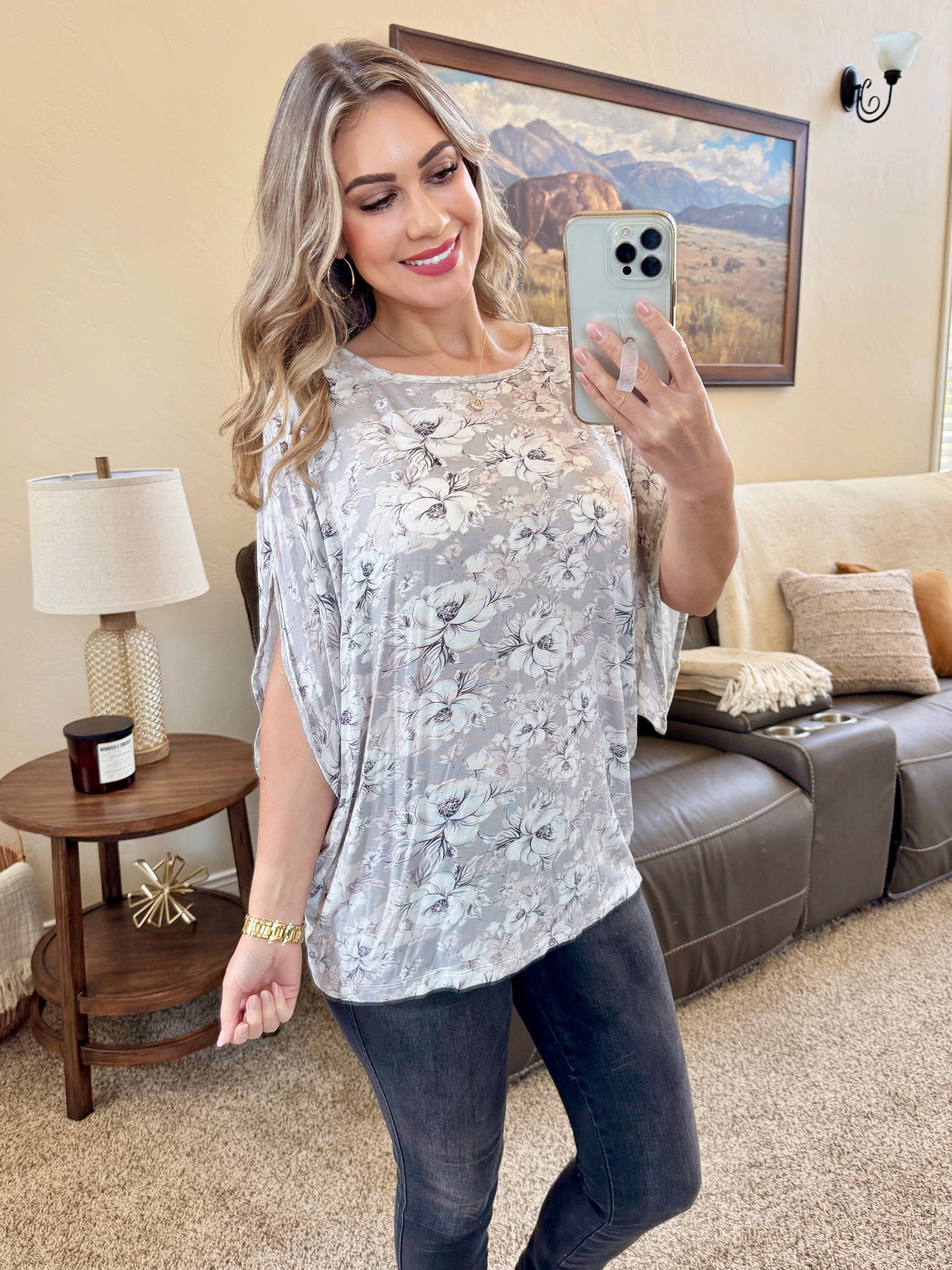 Woman wearing gray dolman sleeve top with white floral print, flowy sleeves, and relaxed silhouette