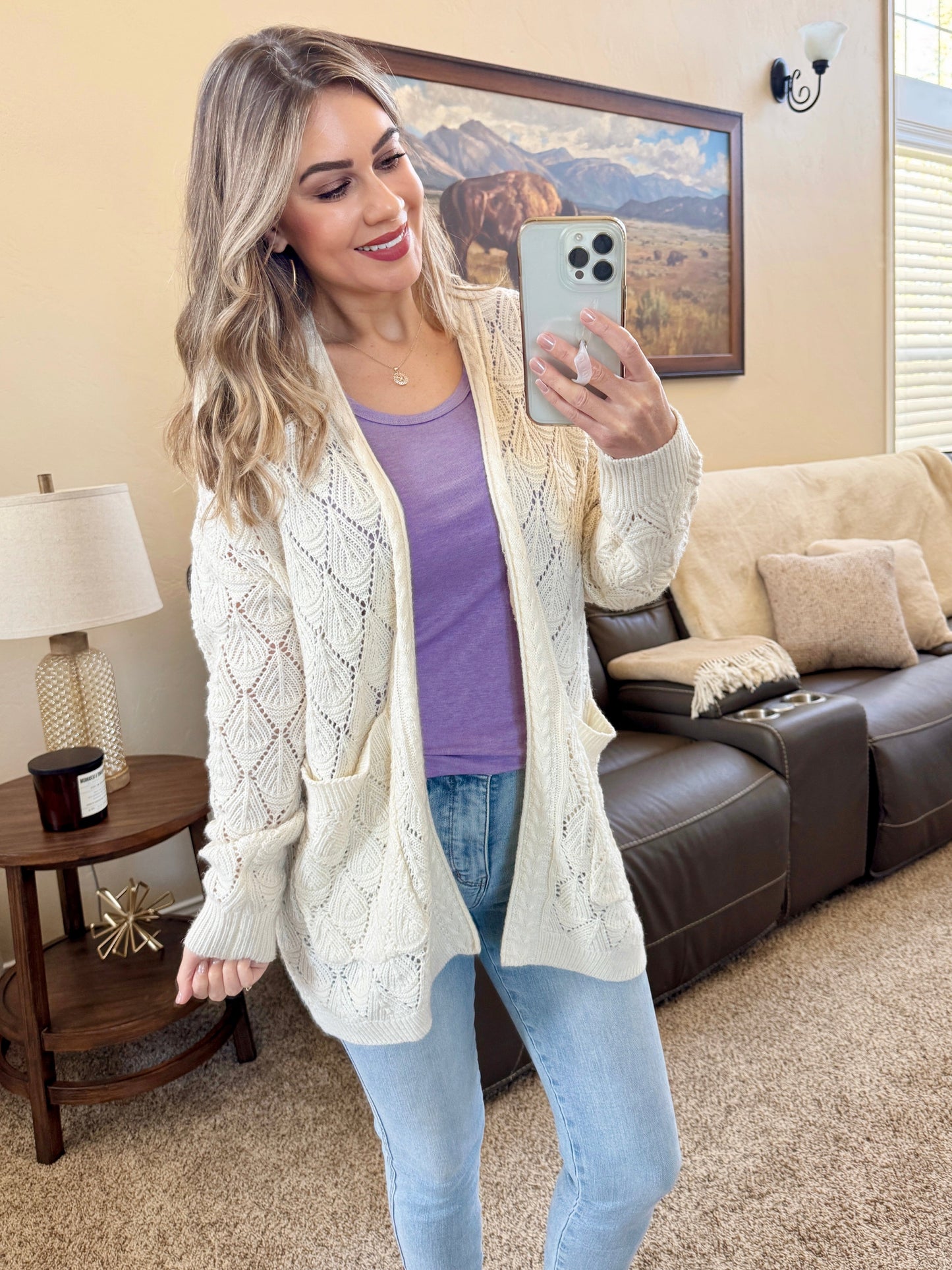 Woman wearing an ivory Open Knit Cardigan with leaf pattern detail and pockets, layered over a tank and jeans
