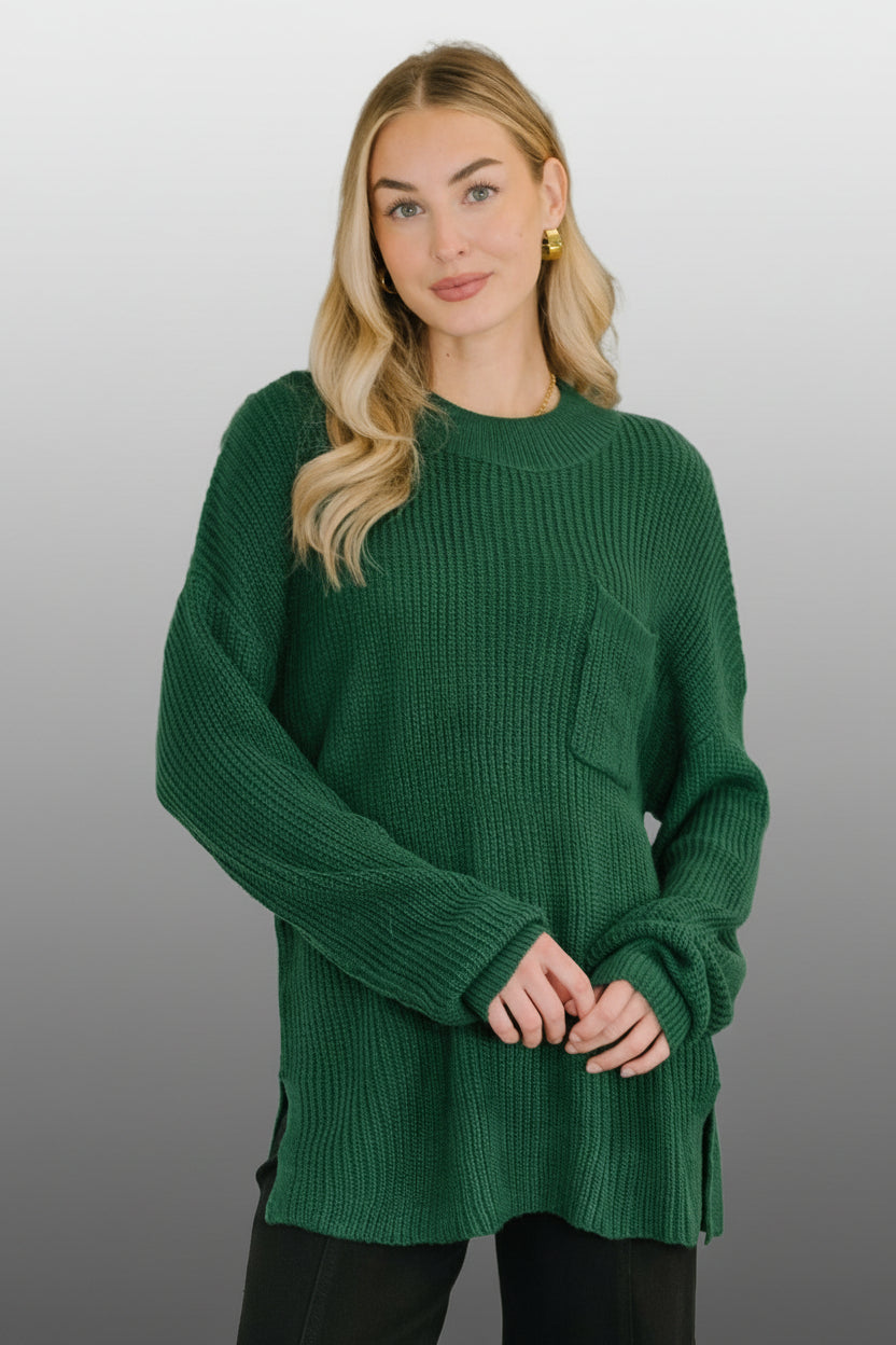 A woman is wearing a hunter green sweater that is knit in a pattern that is ribbed up and down and at the collar.