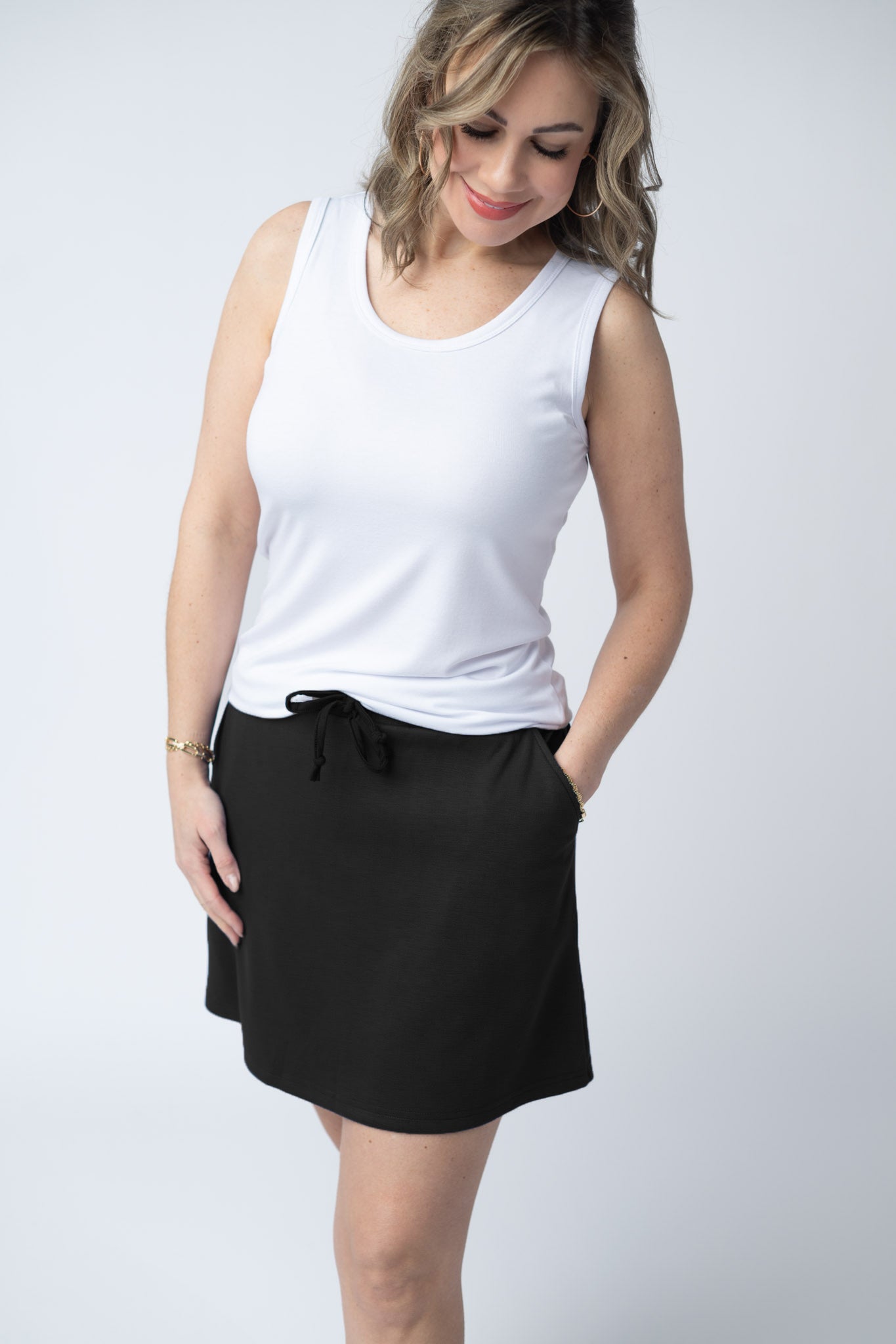Woman wearing the Michelle Mae Serena Luxe Skort in Black, a structured scuba skort with drawstring elastic waist and hidden pockets