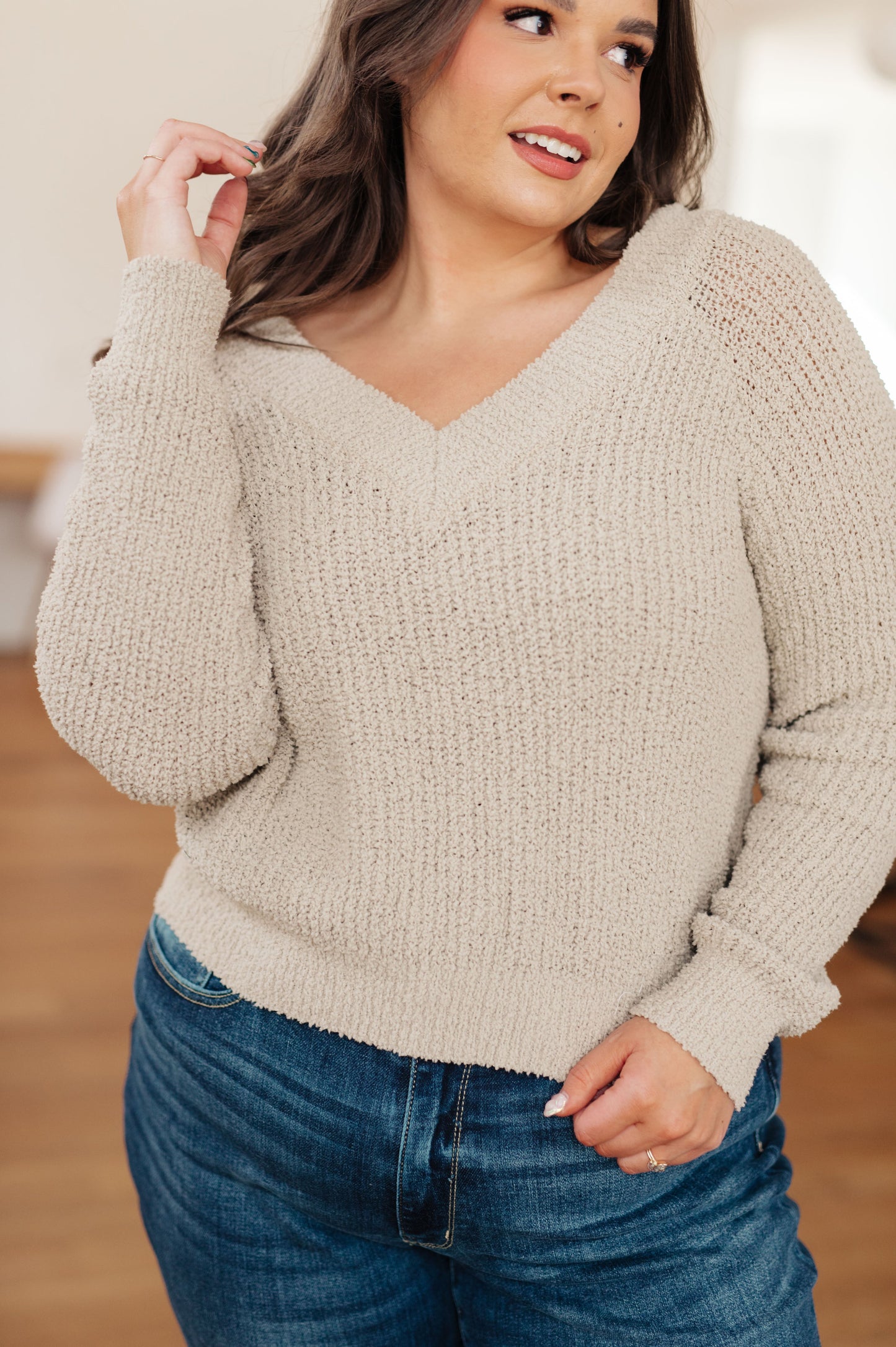Woman is wearing oatmeal-colored ribbed v-neck sweater.