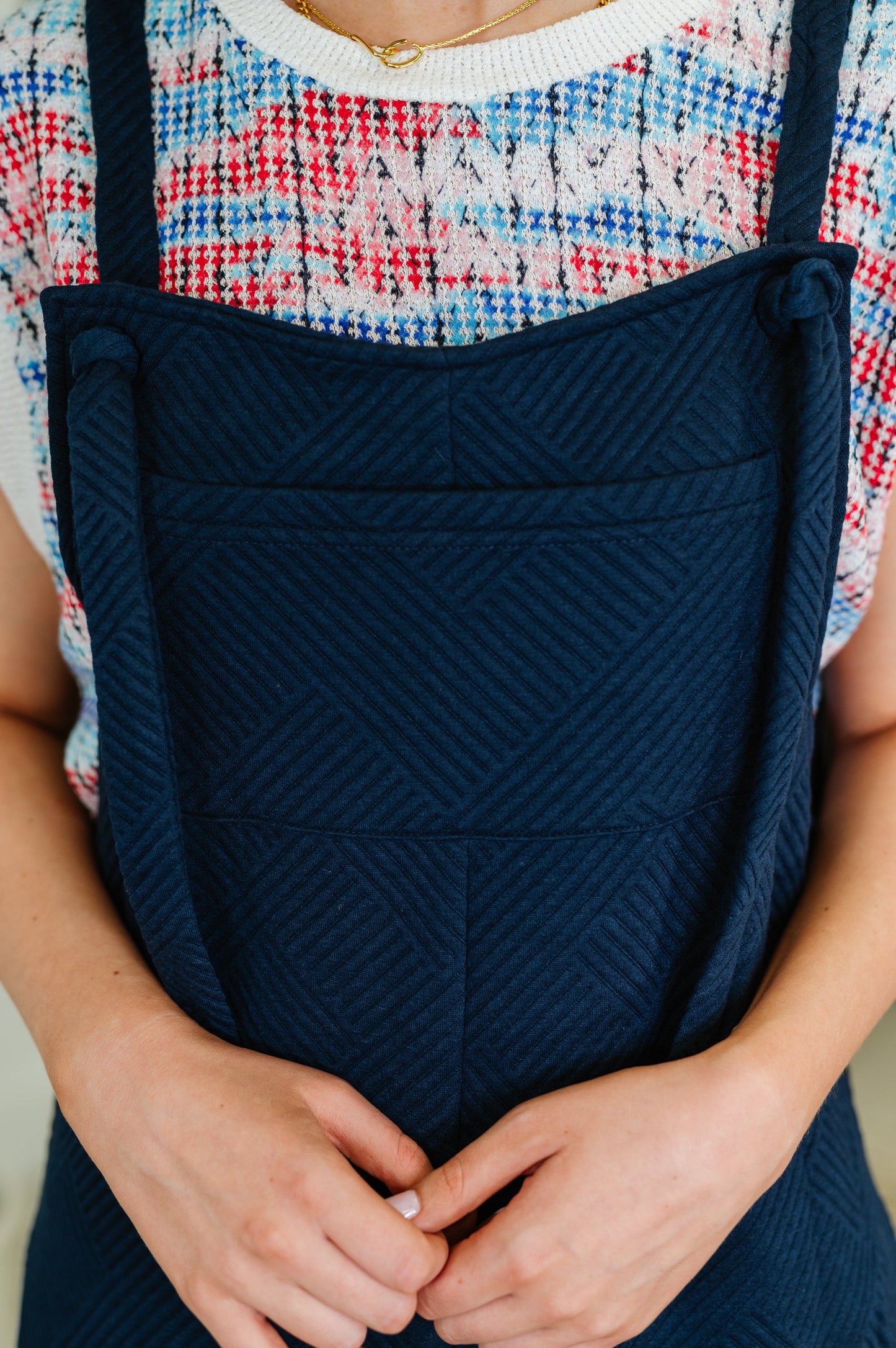 Model wearing navy quilted wide leg jumpsuit with adjustable straps and white sneakers