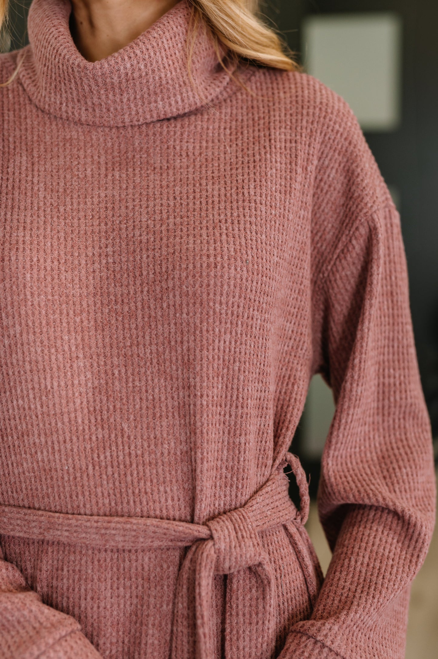 Woman wearing an autumn berry waffle knit maxi dress with turtleneck, long sleeves, and waist tie belt, paired with woven mules
