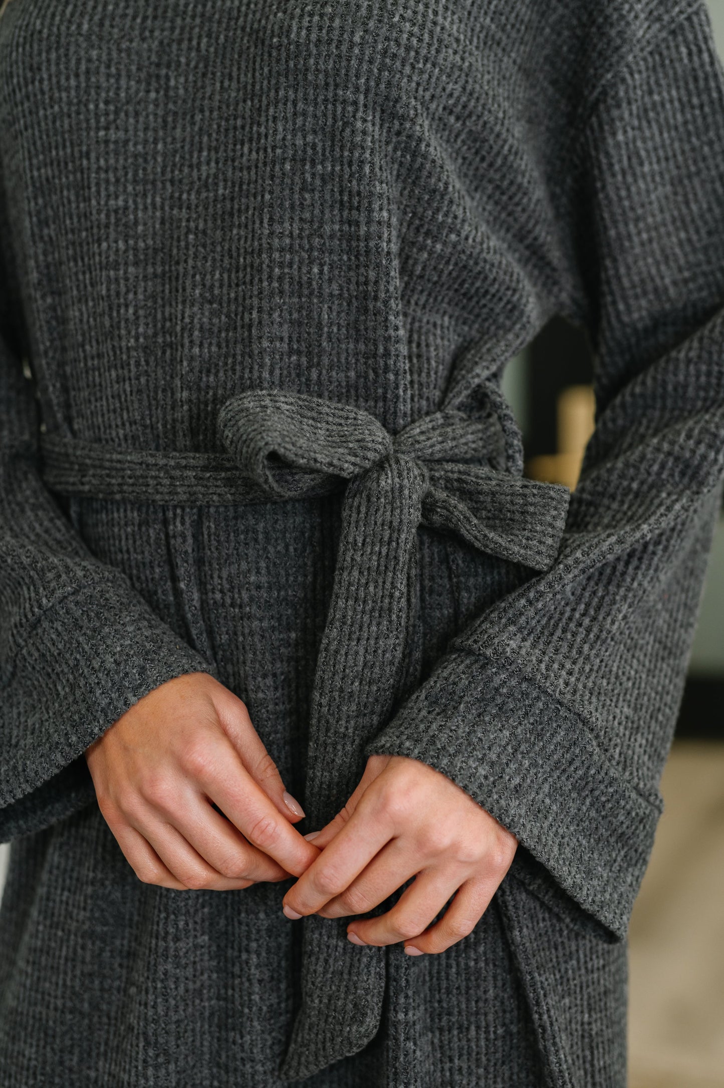 Woman wearing a charcoal gray waffle knit maxi dress with turtleneck, long sleeves, and waist tie belt, paired with black ankle boots