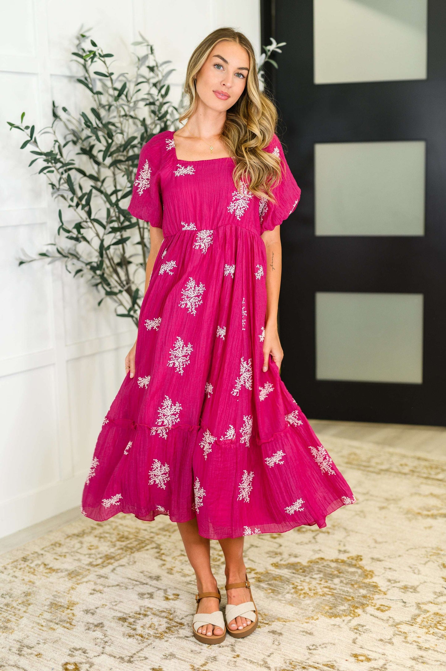 Woman wearing a hot pink embroidered midi dress with square neckline and tiered skirt