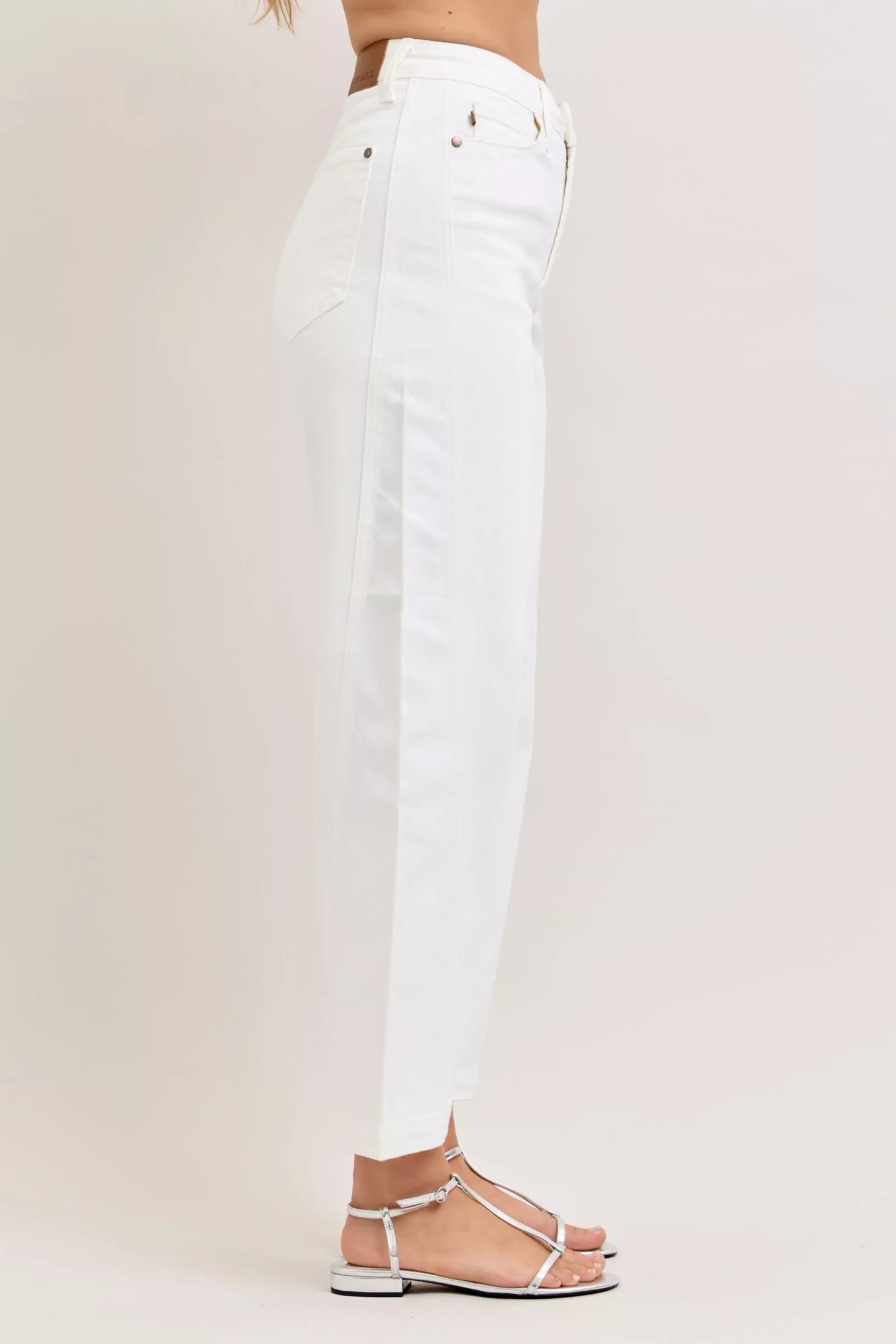 Woman wearing white high rise barrel leg jeans with tapered ankle and silver sandals