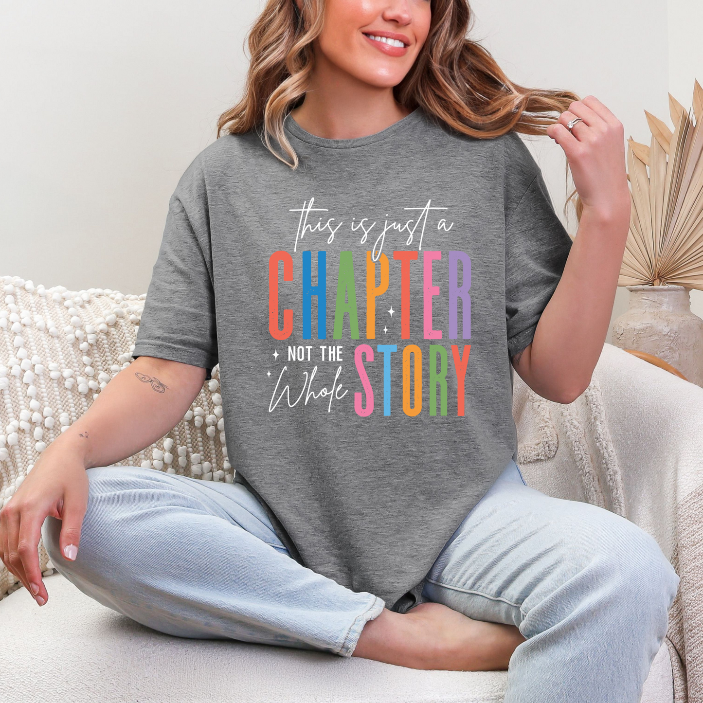 Gray graphic tee with colorful rainbow text reading This Is Just a Chapter Not the Whole Story