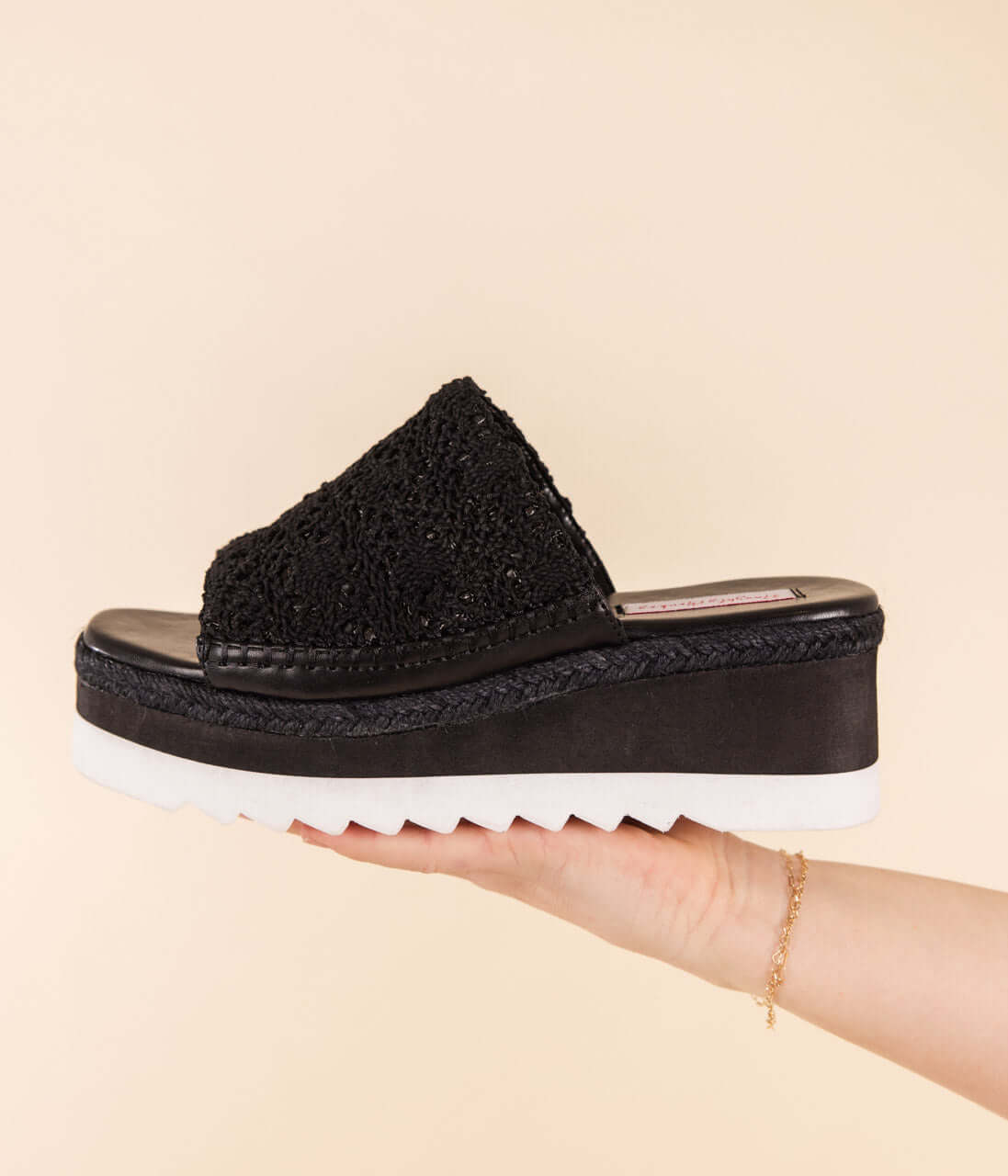 Model wearing black platform sandals with woven upper and cork underlay