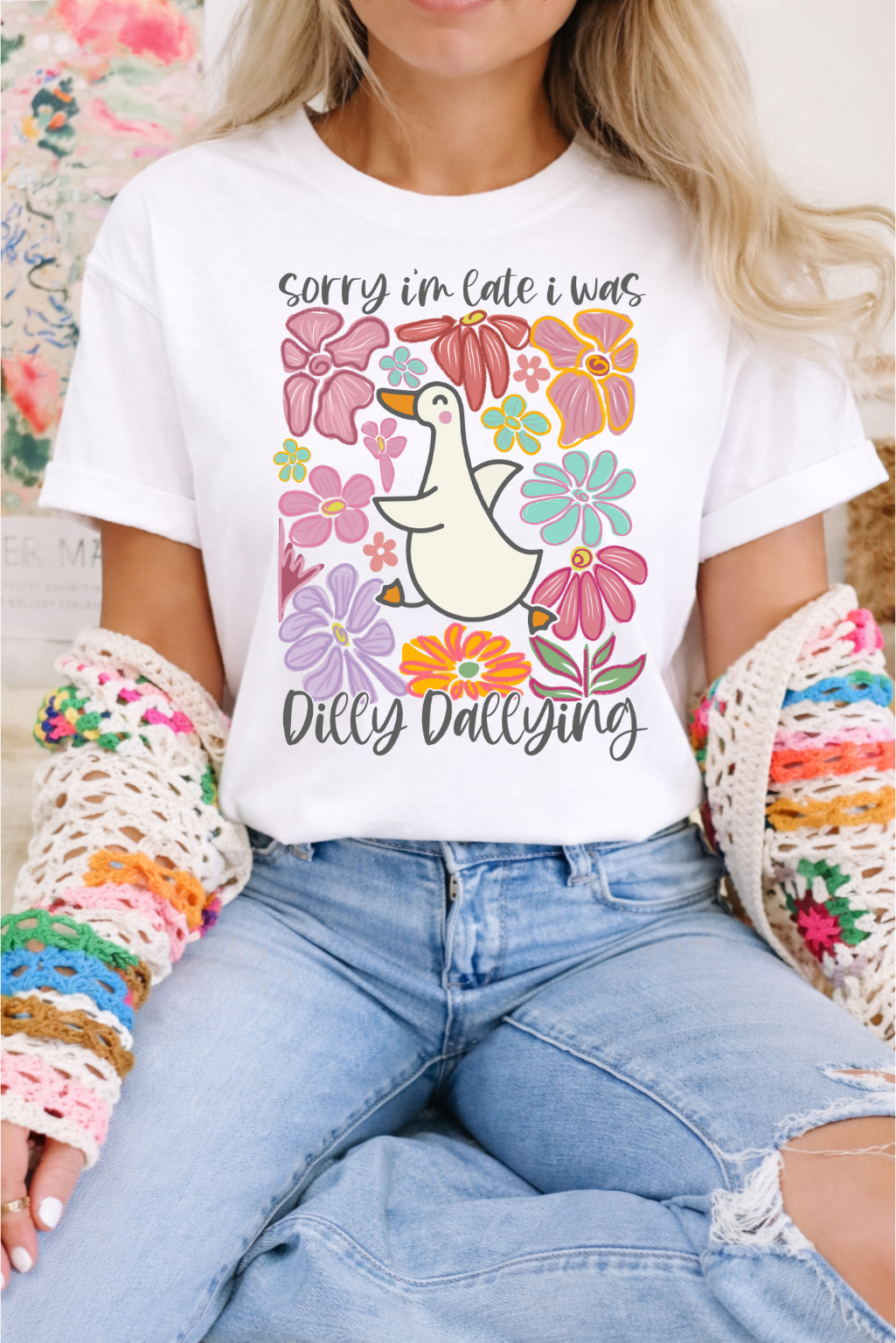 Woman wearing white graphic tee with colorful floral print and cartoon duck with text Sorry I'm Late I Was Dilly Dallying